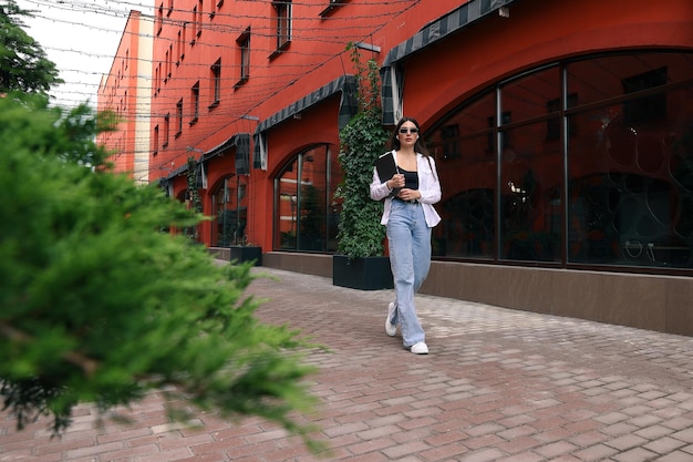 Eine junge Frau mit Kopfhörern und Laptop geht ins Büro zur Arbeit