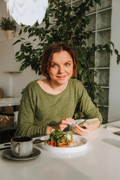 Eine junge Frau mit kurzem Haarschnitt sitzt an einem Tisch in einem Café