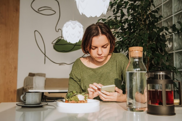 Eine junge Frau mit kurzem Haarschnitt sitzt an einem Tisch in einem Café