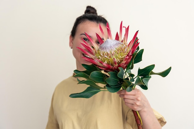 Eine junge frau mit protea-blume auf weißem hintergrund