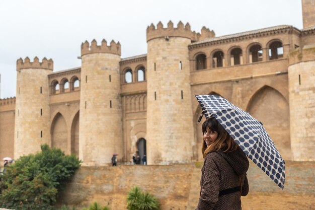 Eine junge Frau mit Regenschirm im Aljaferia-Palast der Hudie-Könige von Saraqusta in der Stadt Zaragoza, neben dem Ebro in Aragon. Spanien