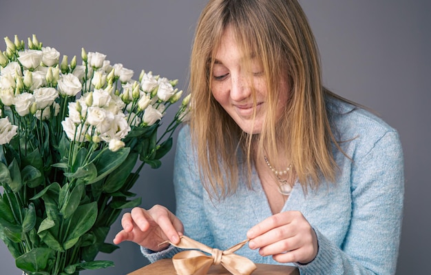 Foto eine junge frau mit rosenstrauß packt eine geschenkbox aus