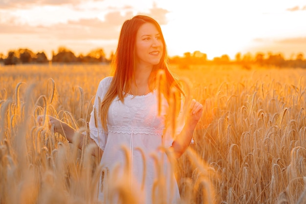 eine junge Frau oder ein Mädchen in einem Feld mit Weizen geht bei Sonnenuntergang spazieren