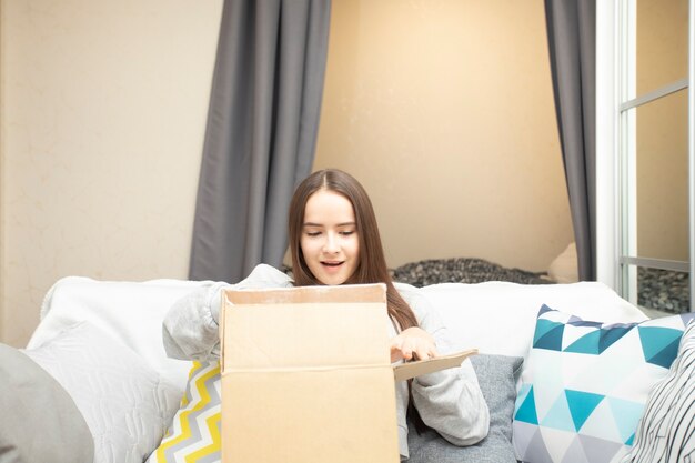 Eine junge Frau schaut verwundert auf einen Karton mit einem Postpaket