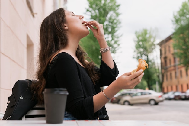 Eine junge Frau sitzt in einem Sommercafé Frühstück im Freien mit Croissant und Kaffee Sommerstimmung