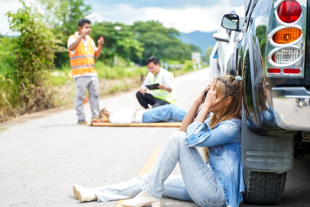 Eine junge Frau sitzt weinend neben dem Auto, mit dem sie auf der Straße mit jemandem zusammengeprallt ist