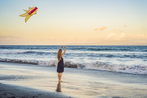 Eine junge Frau startet einen Drachen am Strand. Traumhafte Zukunftspläne