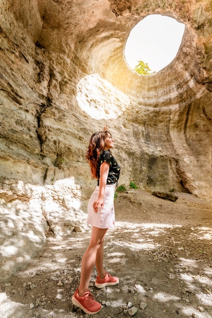 Eine junge Frau steht unter der Erde mit Blick auf ein riesiges Loch im Fels