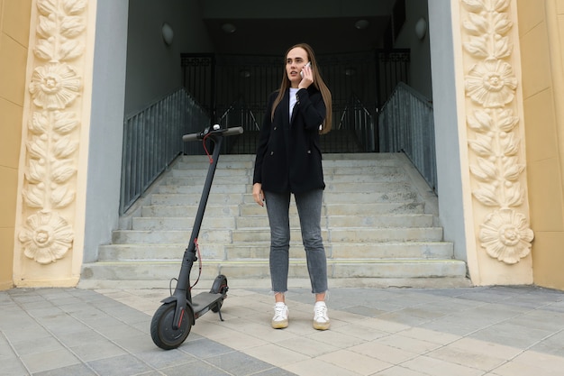 Eine junge Frau telefoniert in der Nähe eines Elektrorollers