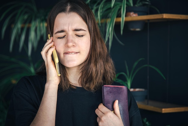 Eine junge Frau telefoniert mit einer Brieftasche in der Hand