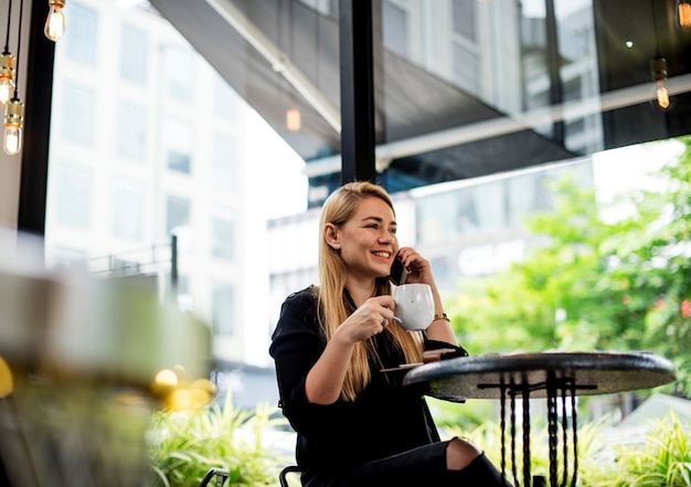 Eine junge Frau trinkt Kaffee und telefoniert