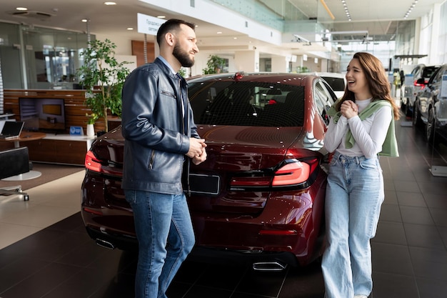 Eine junge Frau überredet ihren Mann in einem Autohaus, ihr ein neues Auto zu kaufen