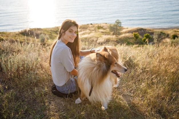 Eine junge Frau und ein älterer Hund gehen an einem Sommerabend auf dem Land spazieren. Eine Dame und ihr treuer Freund aus der Kindheit ein Collie-Hund