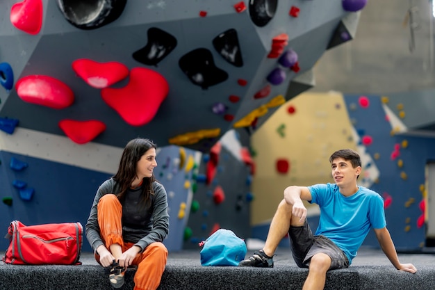 Eine junge Frau und ein junger Mann, die auf einer Kletterwand aufwerfen.