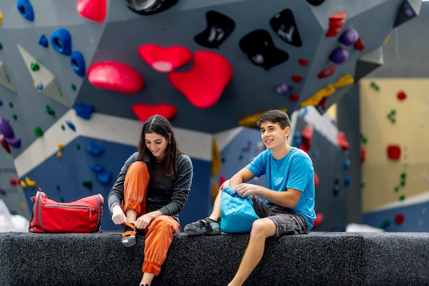 Eine junge Frau und ein junger Mann, die auf einer Kletterwand aufwerfen.