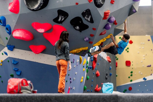 Eine junge Frau und ein Mann, die Kletterwand klettern, üben Klettern.