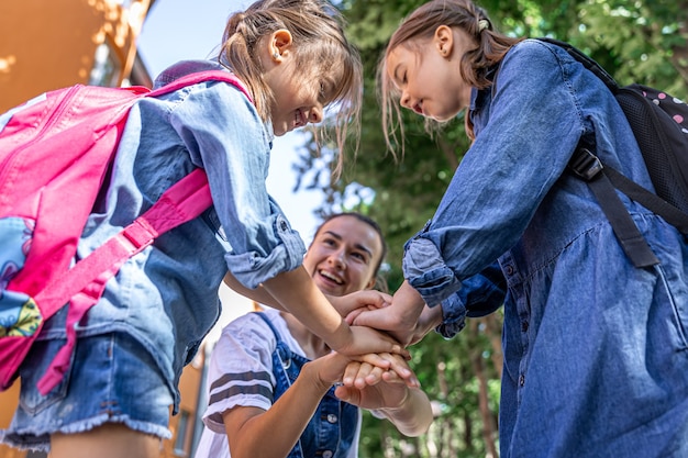 Eine junge Frau unterstützt moralisch die Töchter Händchen haltend ermutigt die Kinder, Mutter begleitet Schüler zur Schule.