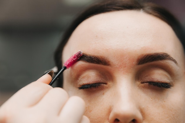 Eine junge Frau unterzieht sich einer Augenbrauenkorrektur in einem Schönheitssalon, Nahaufnahme, das Mädchen malt ihre Augenbrauen im Salon