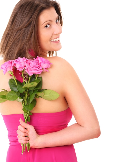 eine junge Frau versteckt einen Strauß rosa Rosen hinter ihrem Rücken über Weiß