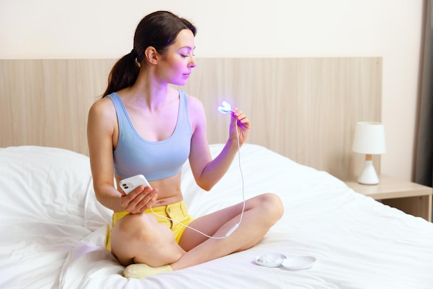 Eine junge Frau verwendet einen Aufhellungskomplex für die Zahnaufhellung zu Hause. USB-UV-Lampe zur Zahnaufhellung