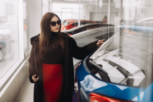 Eine junge Frau wählt ein neues Auto im Autohaus