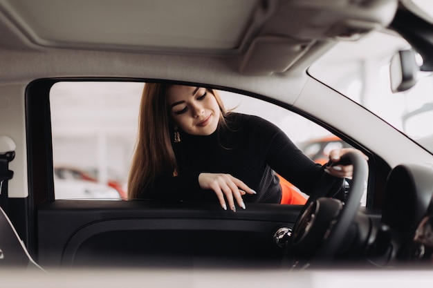 Eine junge Frau wählt ein neues Auto im Autohaus