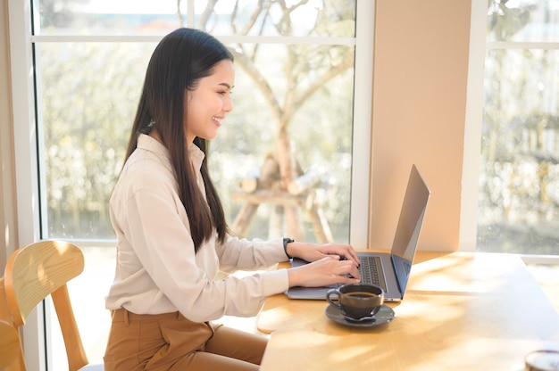 Eine junge Geschäftsfrau, die mit ihrem Laptop im Kaffeehaus arbeitet