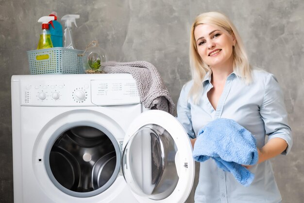 Eine junge Hausfrau mit Waschmaschine und Kleidung. Waschtag.