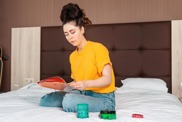 Eine junge hübsche Frau, die auf dem Bett sitzt und eine Zeitschrift liest Home Lesen und Bildung