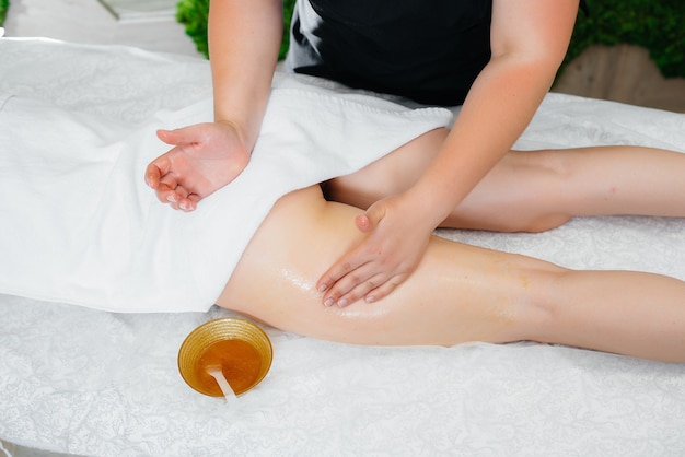 Eine junge hübsche Frau genießt im Spa eine professionelle Massage mit Honig.