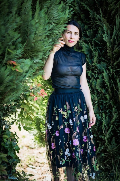Foto eine junge hübsche frau in schwarzer kleidung steht in der nähe eines busches