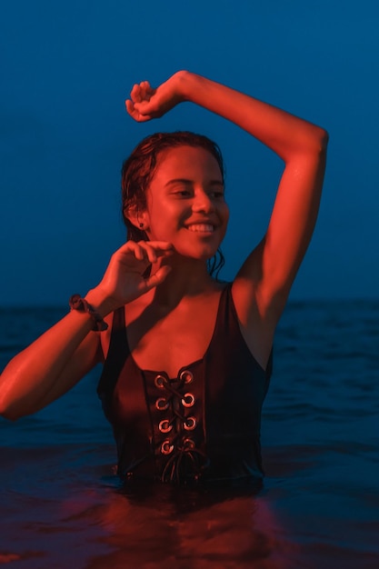 Eine junge kaukasische Brünette, die nachts im Meer mit einem beleuchteten roten Licht badet