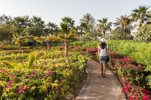 Eine junge kaukasische Touristin in einem weißen Hut geht in einem botanischen Garten mit exotischen Pflanzen spazieren