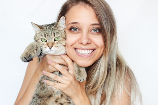 Eine junge lächelnde Frau hält eine Tabby-Katze mit grünen AugenFreundschaft eines Haustieres und seines Besitzers