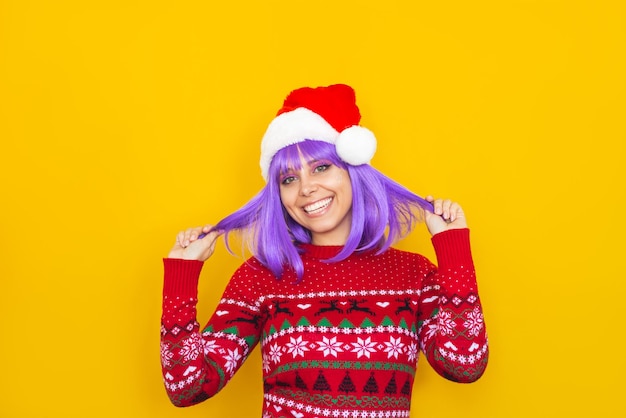 Eine junge lächelnde Frau mit violetten Haaren, einem Hirschpullover und einer Weihnachtsmütze, die Haarsträhnen hält