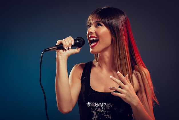 Eine junge lächelnde Sängerin, die ein Mikrofon hält und singt.