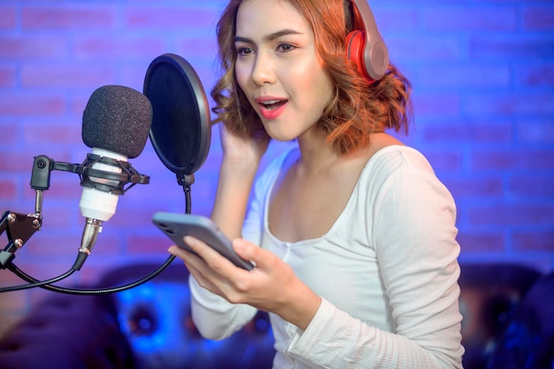 Eine junge lächelnde Sängerin, die Kopfhörer mit einem Mikrofon trägt, während sie ein Lied aufnimmt