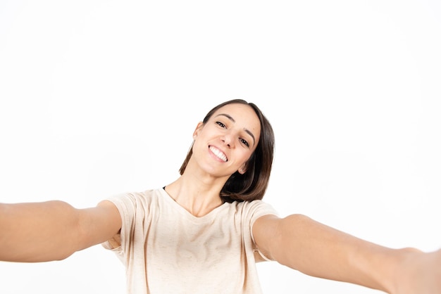 Eine junge lateinamerikanische Frau, die mit zwei Händen ein Selfie macht.