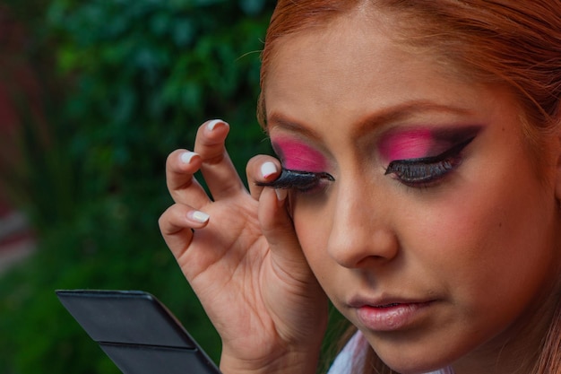 Eine junge mexikanische Tänzerin passt ihr Kleid an und bereitet ihr Make-up für einen traditionellen Tanz vor