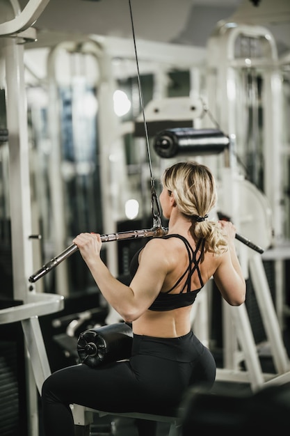 Eine junge muskulöse Frau trainiert im Fitnessstudio an der Maschine.