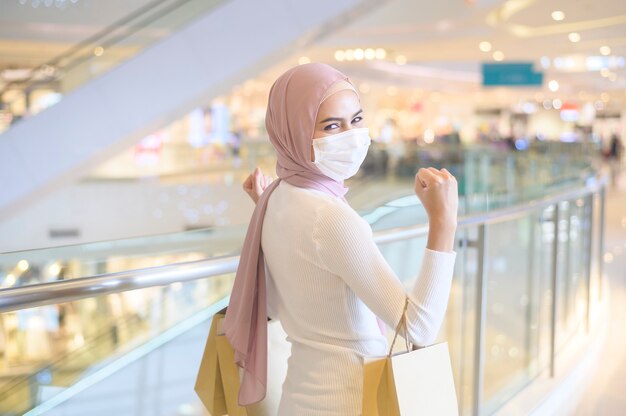 Eine junge muslimische Frau mit Schutzmaske im Einkaufszentrum
