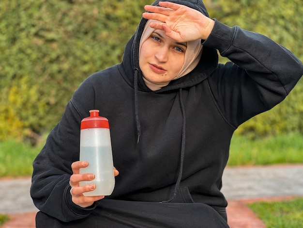 Eine junge muslimische Frau trinkt Wasser nach ihrem morgendlichen Training