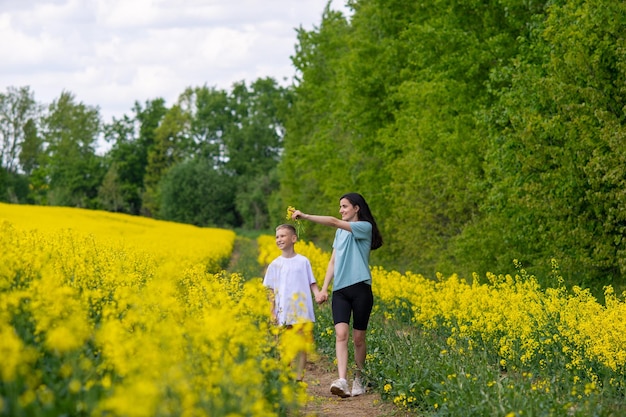 Eine junge Mutter führt ihren Sohn in ein Feld mit gelben Blumen