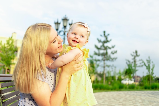 Eine junge Mutter geht im Sommer mit ihrem Baby im Park spazieren und umarmt und küsst die glückliche Mutterschaft