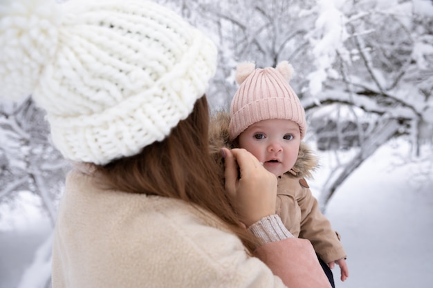 Eine junge Mutter mit einem kleinen Kind spielt im Schnee