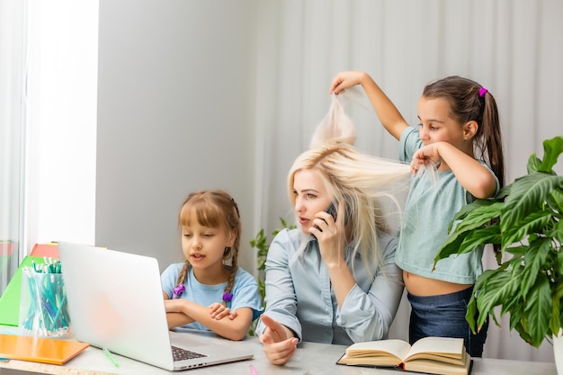 Eine junge Mutter mit zwei Kindern arbeitet von zu Hause aus am Computer. Müdigkeit Lifestyle Hausfrau Freiberuflich. müde Mutter und zwei kleine Töchter