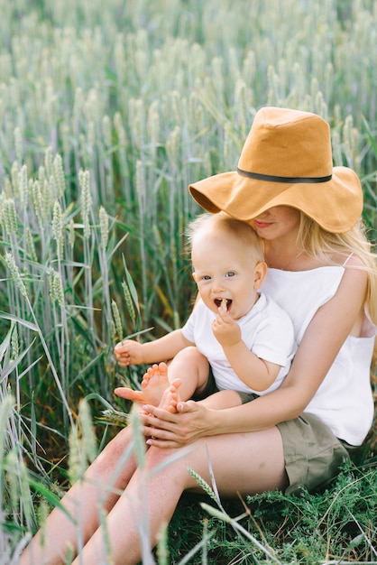 Eine junge Mutter und ihr kleines Kind sitzen in der Nähe des Weizens