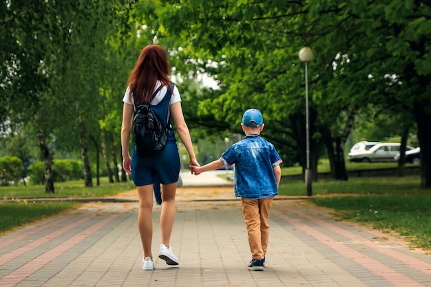 Eine junge Mutter und ihr Sohn spazieren durch den wunderschönen Sommerpark.