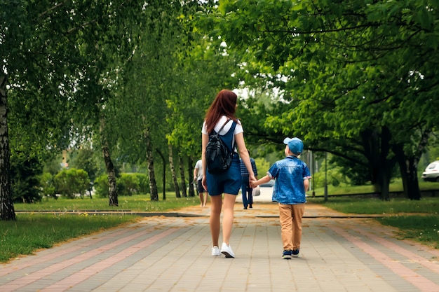 Eine junge Mutter und ihr Sohn spazieren durch den wunderschönen Sommerpark.