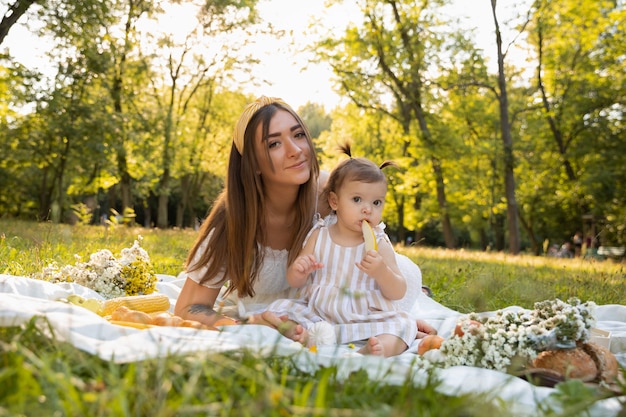 Eine junge Mutter und ihre kleine Tochter machen ein Picknick in einem Stadtpark.